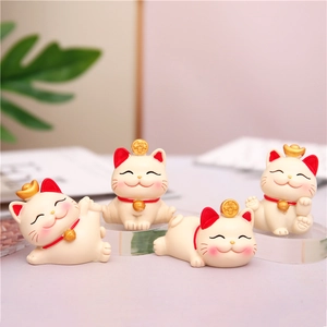 Detailed view of four cute lucky cat ornaments with gold coins for desk decoration