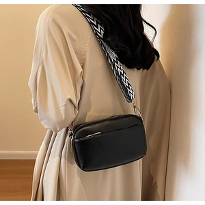 Crossbody square bag with black PU leather finish and woven black-and-white strap