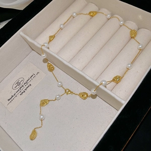 Dettaglio della collana placcata oro con perle bianche e ciondoli a moneta nel portagioielli