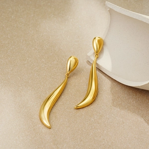 Detail of 18k gold-plated long teardrop earrings with a sleek matte metallic finish