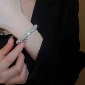 Close-up of pavé crystal threaded open bangle on wrist with black blazer background