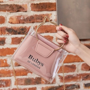 Pink transparent PVC jelly bag with cat-ear handle and chain strap held against brick wall