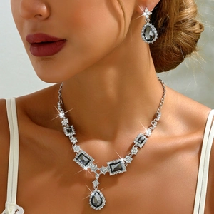 Detailed view of elegant silver necklace and teardrop earrings set with grey crystals