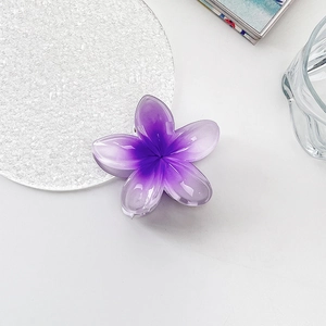 Close-up of translucent purple gradient plumeria hair claw clip on a white table