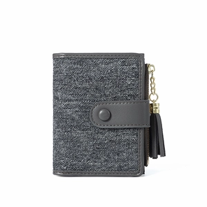 Close-up of gray fabric texture on short wallet featuring button strap and tassel detail