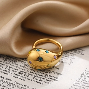Detailed shot of a gold-plated teardrop ring with colorful zircons on vintage book pages