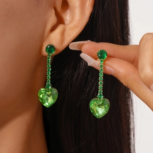 Detailed view of long tassel heart earrings with green faceted crystal and rhinestones