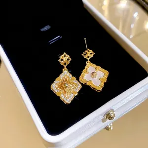 Boucles d'oreilles fleur dorées avec nacre et zircons dans un coffret à bijoux de luxe
