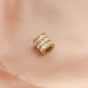Macro detail of a gold cylindrical bead with two rows of clear square-cut crystals