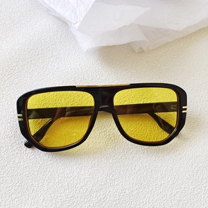 Detailed view of retro pilot sunglasses with black frame and yellow lenses and gold metal bars
