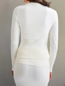 Détail d'un haut en maille blanche à manches longues avec texture côtelée et taille ajustée