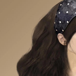 Détail d'un serre-tête en tissu à pois vintage porté sur des cheveux noirs et lisses