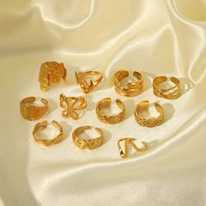 Flat lay of eleven golden stainless steel rings with hammer texture on beige silk fabric