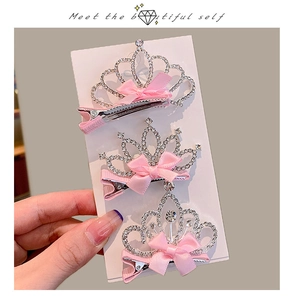 Detailed view of silver crown hair clips with rhinestones and pink satin bows for girls