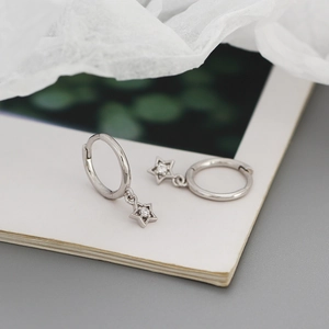 Macro shot of silver S925 star-shaped drop earrings with a centered zircon gemstone