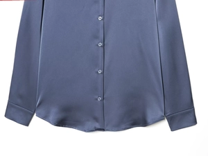 Detailed view of blue satin shirt fabric texture with buttons and smooth silk finish