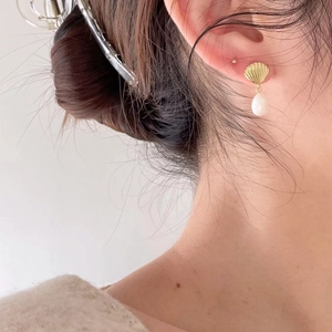 Elegant 925 sterling silver shell earrings with white teardrop pearls on a model