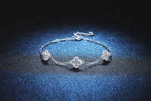 Detail of silver clover bracelet with sparkling Moissanite stones on a textured background