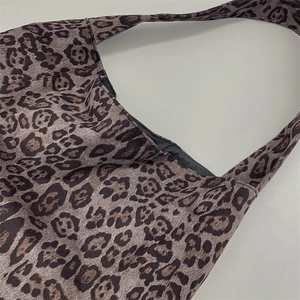 Macro detail of high-capacity tote bag featuring a trendy leopard print fabric texture