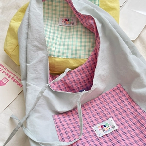 Detail of light blue nylon tote with plaid pocket and colorful brand label embroidery