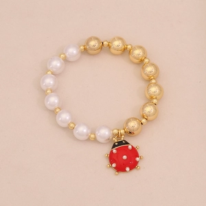 Detail of beaded bracelet with faux pearls, gold beads and a cute red ladybug pendant