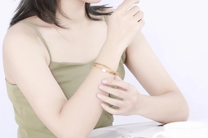 Close-up of golden double-layer stainless steel bracelet with heart shell pendant on wrist