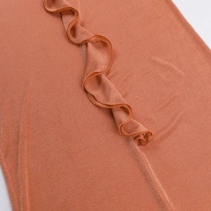 Detail of caramel ruffled edges and fine ribbed knit texture on a backless maxi dress