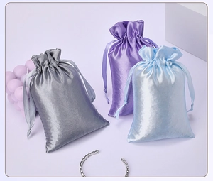 Detailed macro view of satin drawstring gift bags in grey, purple and light blue colors