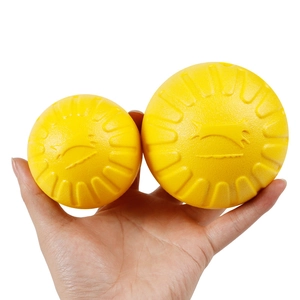 Yellow dog chew balls with grooved texture in two sizes held by hand for dog training