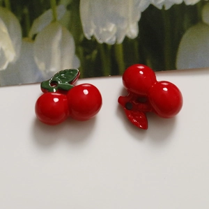 Detailed close-up of DIY acrylic red cherry charms with green leaf for jewelry making