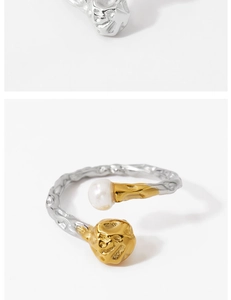Détail d'une bague argentée avec texture martelée, perle blanche et boule lave dorée