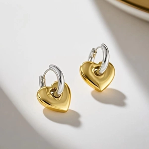 Close-up of heart-shaped earrings with gold pendant and silver hoop dangles