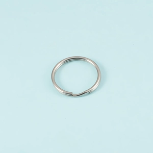 Macro shot of single silver stainless steel split key ring on light blue background