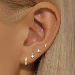 Detail of four-piece gold earring set with diamond studs on model ear for daily wear