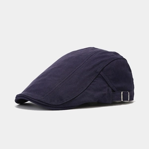 Detail of navy twill flat cap featuring silver adjustable side buckle and neat stitching