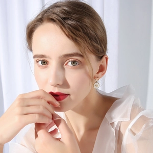 Close-up of model wearing gold shell earrings with circular double C design detail