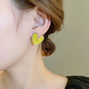 Boucles d'oreilles cœur jaune minimalistes avec bord doré portées pour un style doux