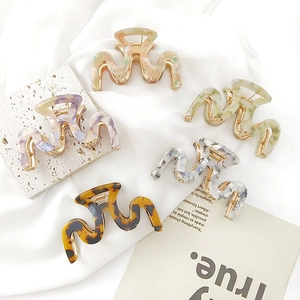 Collection of wavy acetate hair claws in tortoise shell and marble patterns with gold spring