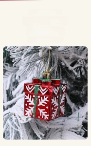 Detailed close-up of a red Christmas gift box ornament with snowflake pattern on pine branch