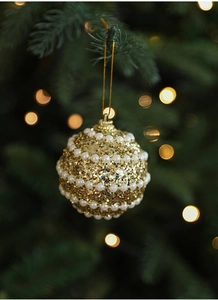 Detailed view of a gold glitter Christmas ornament with pearls hanging on a festive tree