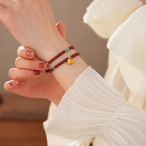 Detail of cinnabar double-layer beaded bracelet with golden pumpkin charm and turquoise accents