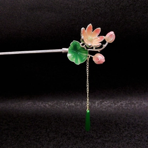 Dettaglio di un fermaglio per capelli a loto con petali smaltati rosa e nappe verdi