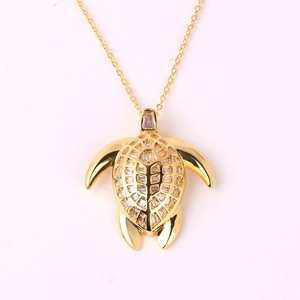 Detailed close-up of golden sea turtle necklace pendant with sparkling clear cubic zirconia