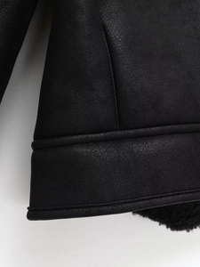 Detailed close-up of the black faux suede jacket seams and soft plush faux fur lining