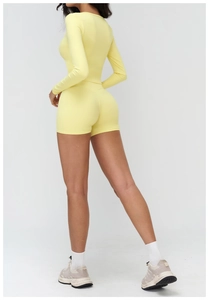 Vue latérale d'un ensemble de yoga jaune avec haut à manches longues et short moulant