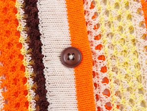 Vue macro détaillée de la texture du tricot à rayures colorées avec un bouton marron