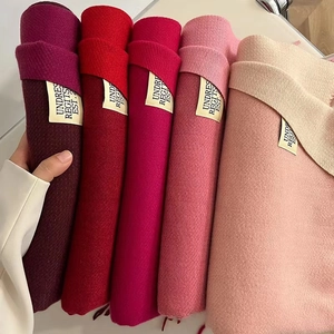 Detail of rolled tassel scarves in deep red, pink and beige with soft cashmere texture