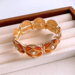Detail of vintage gold round bracelet with orange enamel and pearls in a jewelry box