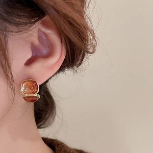 Close-up of model wearing amber resin square studs with gold plated metal frames