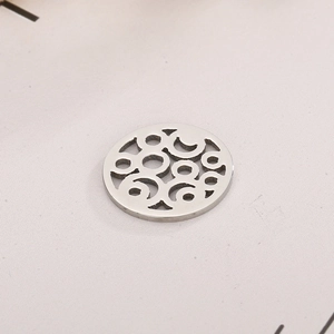 Macro shot of silver circular stainless steel pendant with hollow geometric swirl pattern